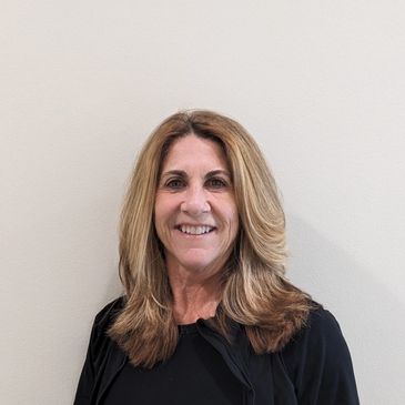 Dianne Carlson smiling against a plain wall
